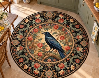 Op de afbeelding: Een rond vloerkleed met een zwarte kraai in het midden die op een tak zit, omringd door rode en crèmekleurige bloemmotieven. De rand heeft een zwarte achtergrond met herhalende bloemmotieven in rood, groen en crèmekleur.