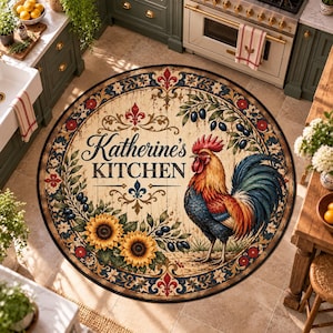 Può includere: Un tappeto da cucina rotondo con un'illustrazione centrale di un gallo, due girasoli e rami d'ulivo. Il testo "Katherine's KITCHEN" è stampato al centro. Il design include un bordo decorativo con motivi a giglio in rosso, blu e crema su uno sfondo effetto legno invecchiato.
