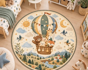 Op de afbeelding: Een rond vloerkleed met een heteluchtballon waarin een beer, een giraf, een konijn en een vos zitten. De achtergrond toont een landschap met bergen, bomen, een rivier, een brug, een zon, een maan en vogels in zachte kleurtinten.
