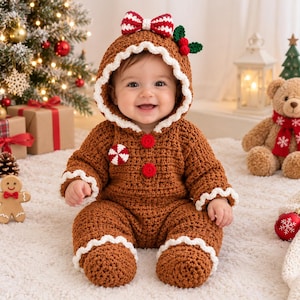 May include: A brown crocheted gingerbread-themed baby onesie with a hood, featuring white scalloped trim, red buttons, a peppermint candy accent, and a red and white striped bow with green holly leaves attached to the top of the hood.