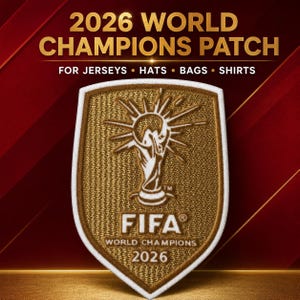 以下が含まれることがあります： 盾形の刺繍ワッペン。金色のトロフィーのアイコン、放射状の線、FIFA WORLD CHAMPIONS 2026の文字、白い縁取りが特徴。ワッペンの上部には2026 WORLD CHAMPIONS PATCH FOR JERSEYS • HATS • BAGS • SHIRTSと記載。