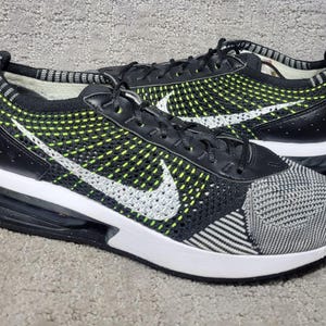 May include: A pair of black and neon yellow athletic sneakers featuring a white Nike swoosh logo on the side, a black and white knit upper, a black heel counter, and a thick white midsole with a visible black air cushioning unit in the heel.