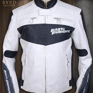 May include: A white and black leather jacket featuring a stand-up collar, a central zipper closure, and two chest pockets with zippers. The chest and sleeves display the text Fast & Furious in white lettering against a black background.