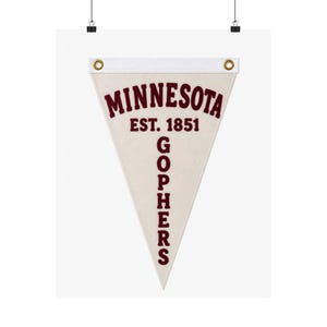 May include: A triangular off-white felt pennant featuring the maroon text MINNESOTA EST. 1851 GOPHERS. The top edge has a white header strip with two brass-coloured metal grommets for hanging, creating a classic sports-themed decorative wall banner.
