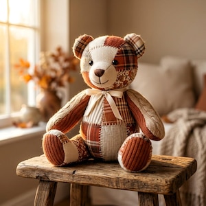 K&ouml;nnte beinhalten: Ein Patchwork-Teddyb&auml;r aus verschiedenen Stofftexturen, darunter braun-wei&szlig; karierte Muster, Fischgr&auml;tmuster, Zopfstrick und florale Designs. Der B&auml;r hat schwarze Knopfaugen, eine gestickte Nase und einen Mund sowie eine cremefarbene Schleife.