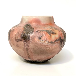 May include: A round ceramic vase with a textured, mottled glaze in shades of pink, brown, and white.