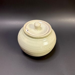 May include: A white ceramic sugar bowl with a lid and a small spout. The bowl has a textured design of small circles.