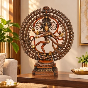 Puede incluir: Una estatua de tono bronce de la deidad Shiva Nataraja bailando dentro de un anillo circular de fuego, conocido como prabhamandala. La figura tiene múltiples brazos, se apoya sobre un pequeño demonio y está montada sobre una base rectangular.