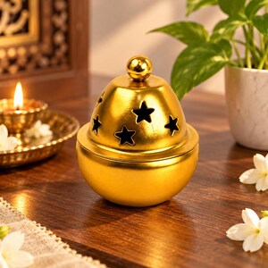 May include: A metallic gold incense burner with a rounded base and a removable dome-shaped lid. The lid features a small spherical knob at the top and multiple star-shaped cutouts that allow smoke to escape from the interior chamber.