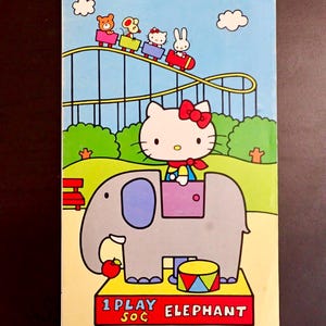 May include: A vintage Hello Kitty themed box featuring a roller coaster scene with cartoon characters and Hello Kitty riding an elephant. The box is rectangular, with dimensions of approximately 9.4 x 5.1 inches, and includes the text "1 PLAY ELEPHANT".