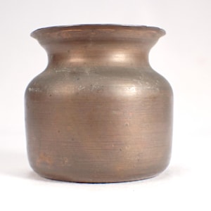 May include: A small, round, copper vase with a slightly flared lip. The vase has a smooth, polished surface and a warm, metallic color.