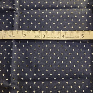 Può includere: Tessuto blu navy con un motivo a piccoli crocini bianchi. Un metro a nastro mostra 12.7 cm. Il nastro recita "HARA MADE IN JAPAN FIBERGLASS TAPE".