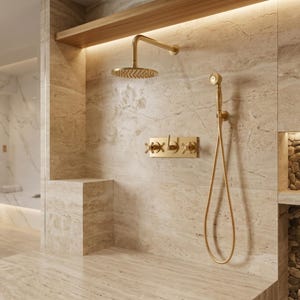 May include: A brushed gold shower system featuring a round overhead rainfall showerhead, a handheld shower wand with a flexible hose, and a wall-mounted control panel with two cross-handle valves and a central lever, set against beige stone tiles.