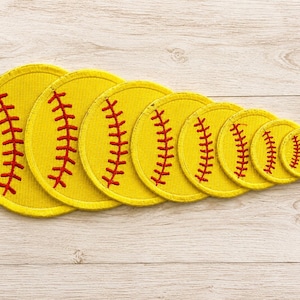 May include: A set of eight circular yellow embroidered patches, each featuring red stitching that mimics the laces of a softball. The patches are arranged in a row, decreasing in size from left to right, showcasing a consistent design.