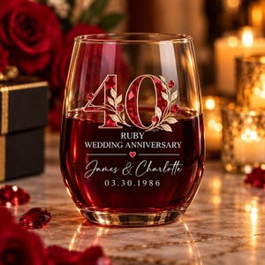 May include: A clear stemless wine glass filled with deep red liquid, featuring the number 40 in a ruby-red gemstone pattern with gold leaves. Text reads: RUBY WEDDING ANNIVERSARY, James & Charlotte, and the date 03.30.1986 with a small red heart.