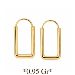 May include: A pair of gold-toned hoop earrings with a rectangular shape and rounded corners. The earrings feature a thin wire post closure at the top. The text 0.95 Gr is printed below the earrings, indicating the weight in grams.