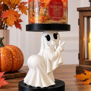 Peut inclure: Un bougeoir en forme de fantôme blanc avec une base et une plateforme supérieure circulaires noires. La figurine de fantôme a de grands yeux noirs, de longs cils et fait un signe de paix. Une bougie Mainstays Warm Fall Leaves de 368g est posée dessus.