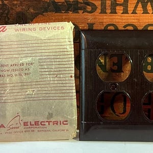 May include: An image of a vintage electrical outlet cover and a package of Sierra Electric wiring devices. The outlet cover is dark brown with four openings. The wiring device package is off-white with red text and the text "Sierra Electric Corporation".