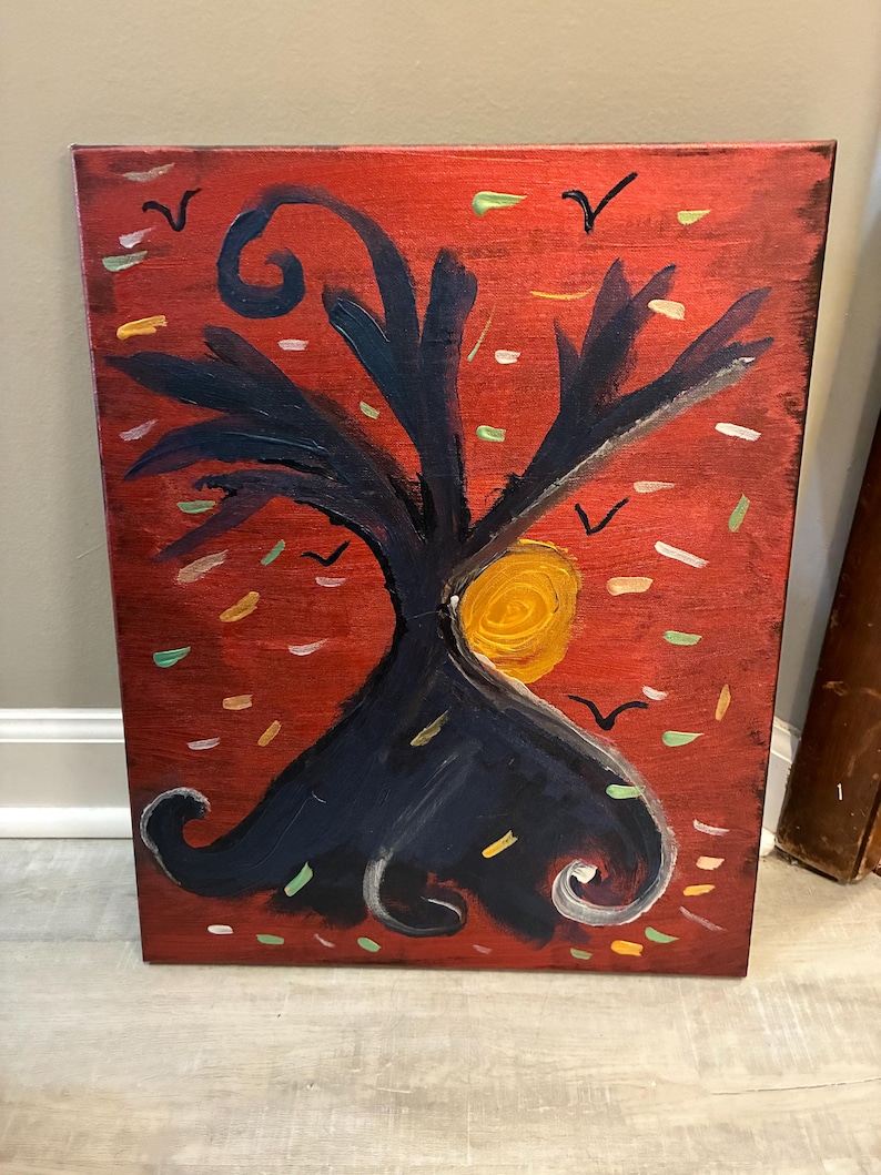 May include: A rectangular canvas painting featuring a dark blue, stylized tree with swirling branches centered against a vibrant red background. A bright yellow circular sun is positioned behind the tree, surrounded by small black bird silhouettes and scattered dashes of green, white, and gold paint.