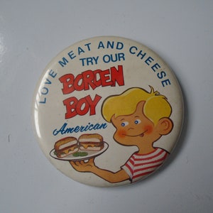 May include: A round button with a cartoon boy holding a plate with two hamburgers. The button says "Love Meat and Cheese Try Our Borden Boy American".