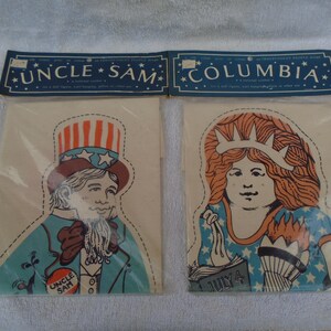 May include: Two separate fabric panels in clear plastic packaging featuring printed illustrations of Uncle Sam and Columbia. Each panel has a blue header card with white text reading UNCLE SAM and COLUMBIA, including dashed cut lines.