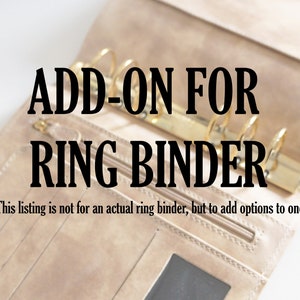 Può includere: Primo piano di un raccoglitore ad anelli in pelle beige con anelli dorati. Il testo "ADD-ON FOR RING BINDER" è stampato in nero sul davanti. Il testo "This listing is not for an actual ring binder, but to add options to one" è stampato in nero sotto il titolo.
