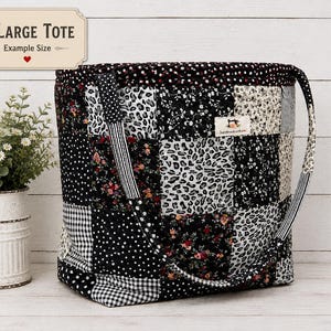 Op de afbeelding: Een grote draagtas gemaakt van een patchwork van zwarte, witte en grijze stoffen met diverse patronen, waaronder luipaardprint, bloemmotieven, stippen en vichy-ruitjes. Aan de voorzijde is een klein rechthoekig label vastgenaaid.