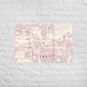 Può includere: Una stampa cartografica rettangolare di Tempe, Arizona, con linee stradali color marrone scuro su sfondo crema. Un piccolo cuore marrone scuro segna una posizione centrale. Il testo TEMPE è stampato in marrone scuro, con Arizona State University e coordinate sotto.