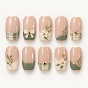 May include: A set of ten press-on nails featuring a nude base with sage green accents. Designs include a plaid pattern with gold lines, a cream-colored bow, white floral appliques, gold heart charms, and delicate painted green leaf sprigs.