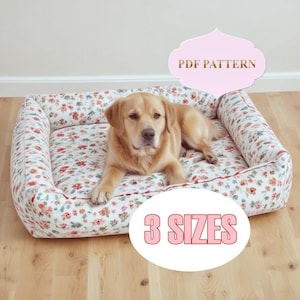 Puede incluir: Un patrón PDF para una cama de perro en tres tamaños. La cama está hecha de tela blanca con estampado floral y tiene un borde elevado. Un perro golden retriever está acostado en la cama.