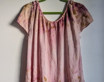 May include: A pink, brown and gold tie-dye top with a scoop neck and short sleeves. The top is hanging on a green hanger.