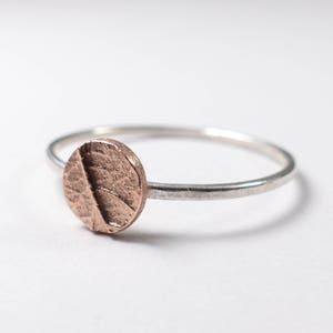 May include: A silver band ring with a textured copper circle on top.