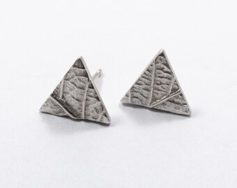 May include: A pair of silver triangle earrings with a textured surface.