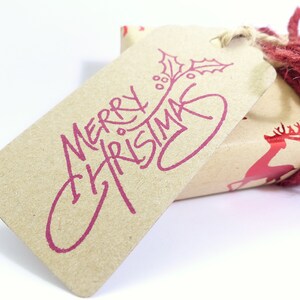 May include: A brown paper gift tag with a red "Merry Christmas" message and a holly sprig design.