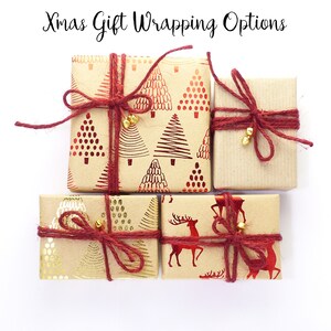 May include: Four Christmas gift boxes wrapped in brown paper with red and gold designs. The boxes are tied with red twine and have gold bells attached.