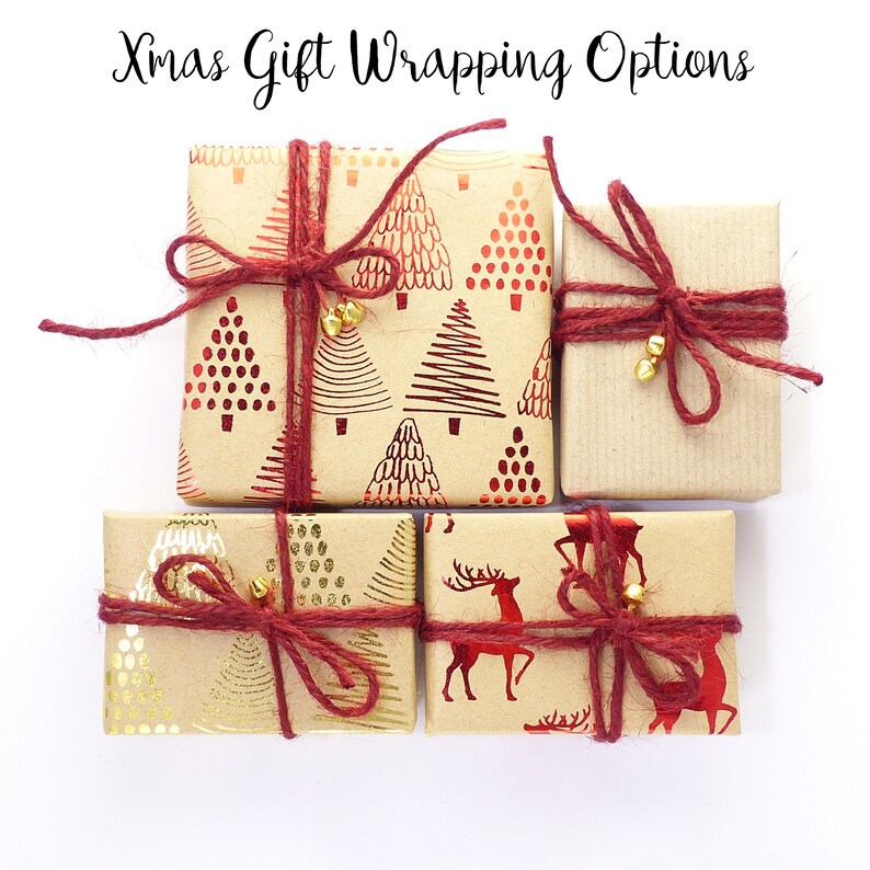 May include: Four Christmas gift boxes wrapped in brown paper with red and gold designs. The boxes are tied with red twine and have gold bells attached.