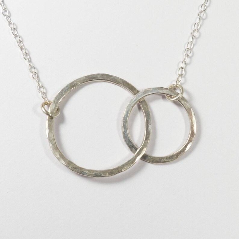 May include: A silver necklace with two interlocking hammered circles.