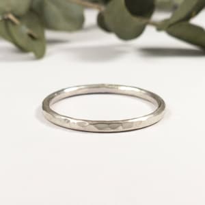 May include: A simple silver band ring with a hammered texture.