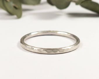 May include: A simple silver band ring with a hammered texture.