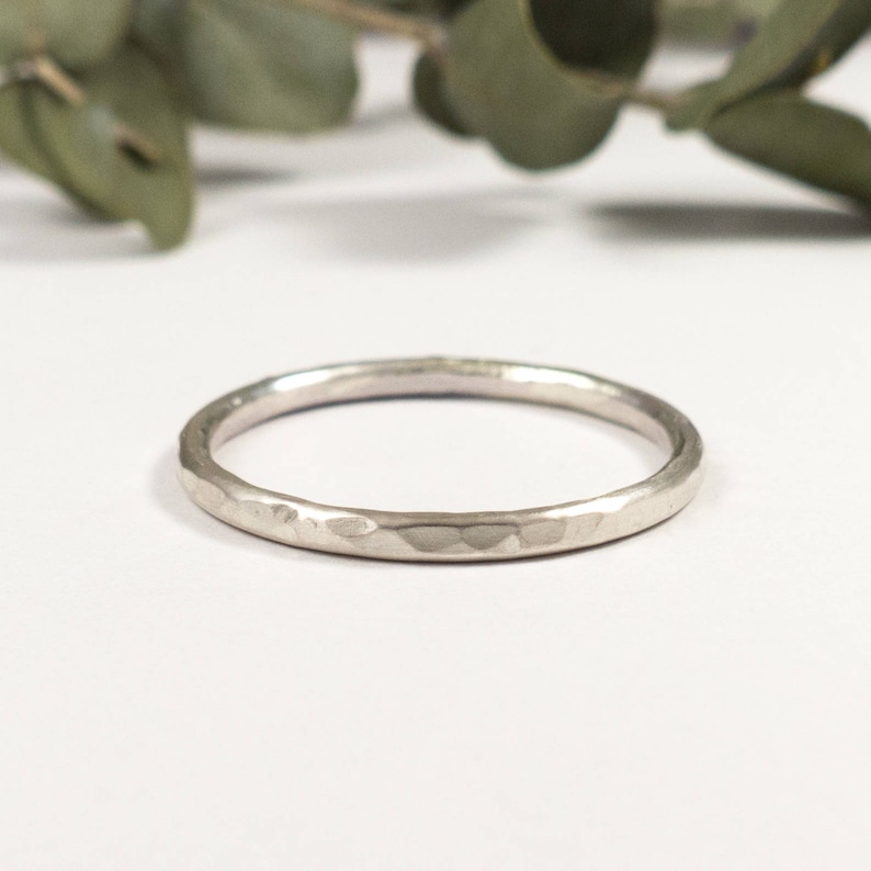 May include: A simple silver band ring with a hammered texture.