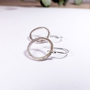 May include: A pair of silver hammered circle earrings with a simple hook closure.
