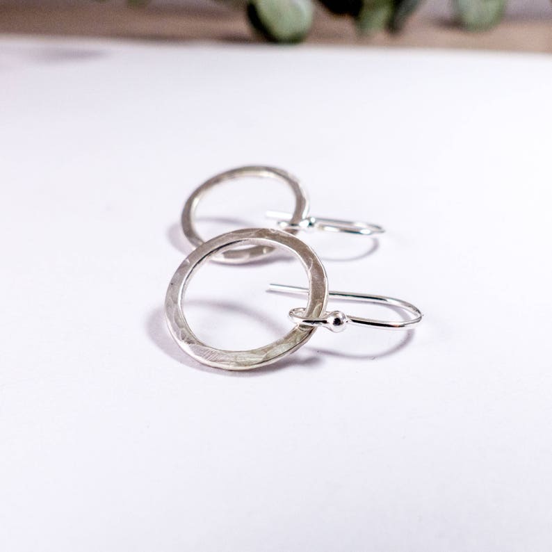 May include: A pair of silver hammered circle earrings with a simple hook closure.