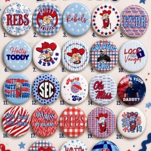 May include: A collection of twenty-three round pinback buttons featuring various designs in red, white, and blue. The buttons display text such as "game day BUTTONS," "REBS," "Hotty TODDY," "Ole Miss," and "GO REBELS," alongside illustrations of mascots, patterns, and sports themes.