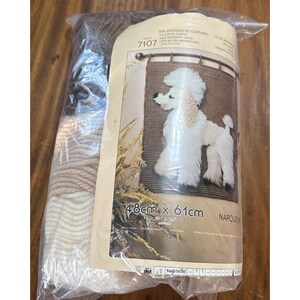 May include: A sealed craft kit for a latch hook rug featuring a white poodle design on a brown background. The packaging displays the text 48cm x 61cm, 19 inches x 24 inches, and Napoleon. It includes various shades of yarn in white, beige, and brown.