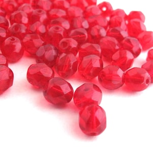 May include: A pile of red faceted glass beads. The beads are small and round, with a shiny finish.