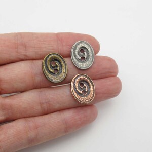 May include: Three metal buttons with a swirl design. The buttons are in silver, copper, and bronze.