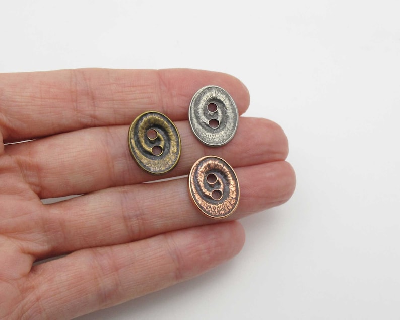 May include: Three metal buttons with a swirl design. The buttons are in silver, copper, and bronze.