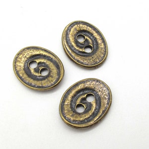 May include: Three oval-shaped buttons with a swirl design. The buttons are a dark bronze color with a gold sheen.