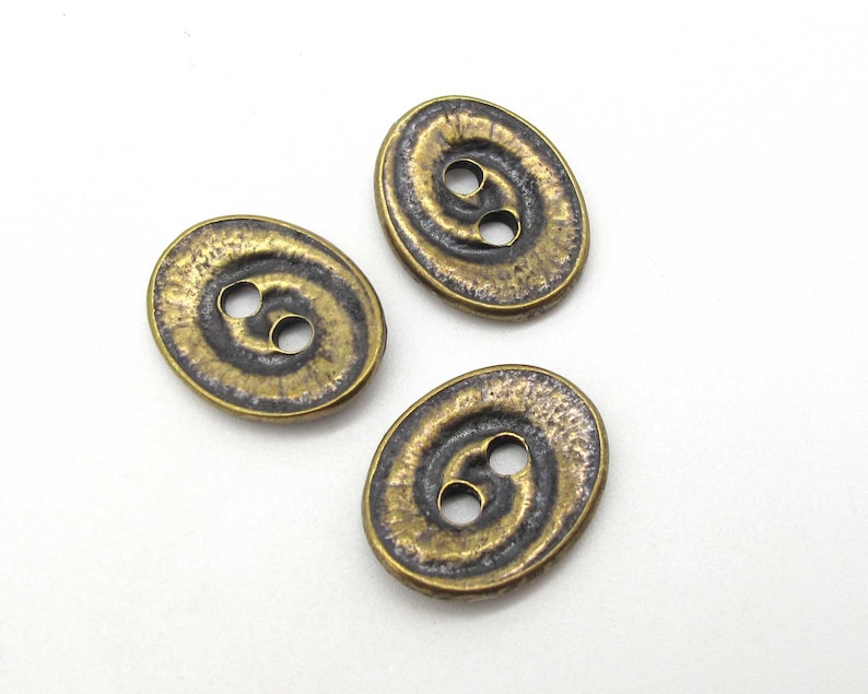 May include: Three oval-shaped buttons with a swirl design. The buttons are a dark bronze color with a gold sheen.