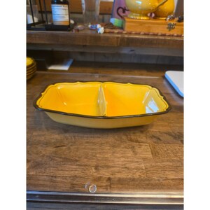 May include: A rectangular, two-section serving dish with a bright yellow interior and exterior. The dish features a dark brown rim with a scalloped edge design, creating a distinct contrast against the vibrant yellow color of the ceramic material.